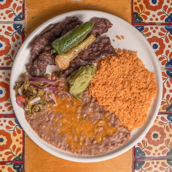 Don Pedro Mexican Restaurant's carne asada plate with rice, beans, guacamole, and grilled peppers.