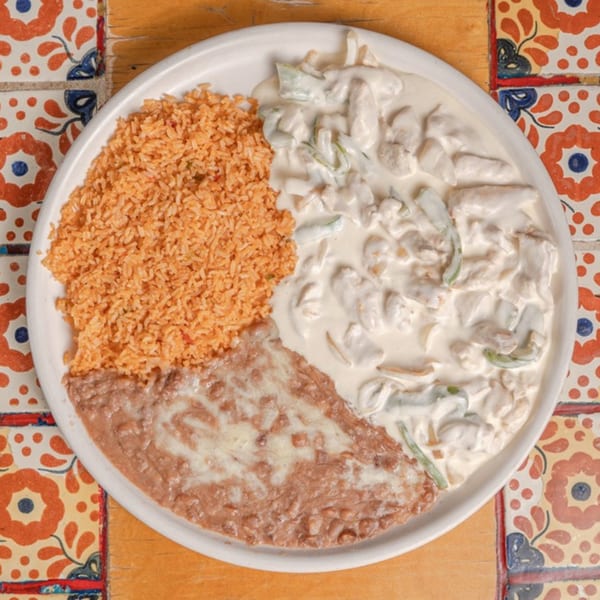 Don Pedro Mexican Restaurant's creamy chicken dish with rice and refried beans on a decorative tiled table.